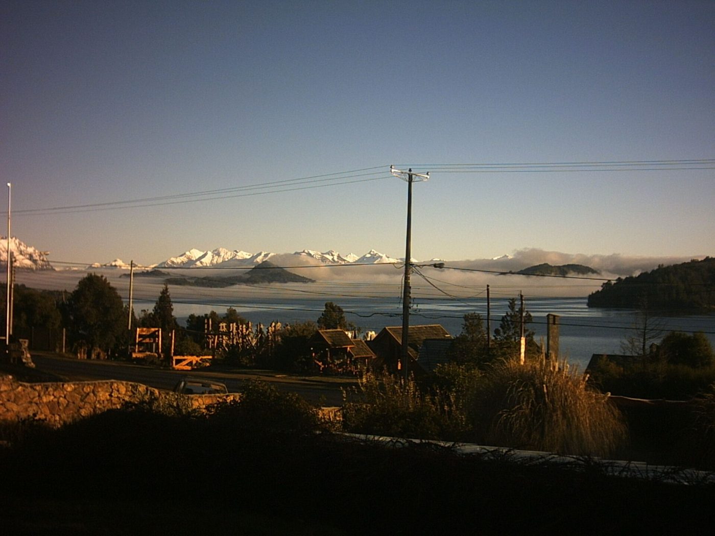 A quiet road above San Carlos de Bariloche at first light, with timber houses, the lake below and the snow-covered Andes on the far shore